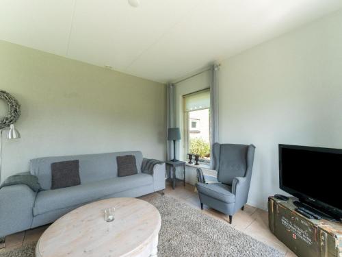 a living room with a couch and a table and a tv at Holiday home with wide views and garden in Balkbrug