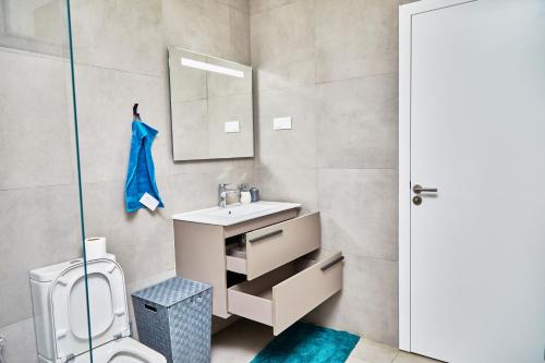 a bathroom with a sink and a toilet and a mirror at Waypoint Suites in Dakar