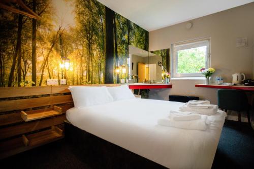 1 dormitorio con 1 cama blanca grande y un mural forestal en Metro Inns Newcastle, en Newcastle
