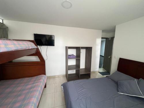 a bedroom with two beds and a tv and a mirror at Hotel Playa Blanca in Tota