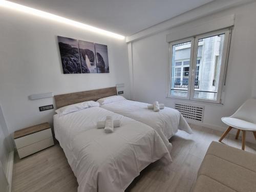 1 dormitorio blanco con 1 cama grande y 1 silla en 131A - Espectacular apartamento 8 personas Puerto, en Gijón