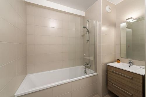 een witte badkamer met een bad en een wastafel bij Les 4 Elements - Apt A11 - BO Immobilier in Châtel