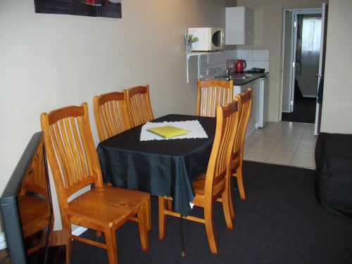 a dining room with a table and chairs and a kitchen at Sun Valley Motel in Wellsford