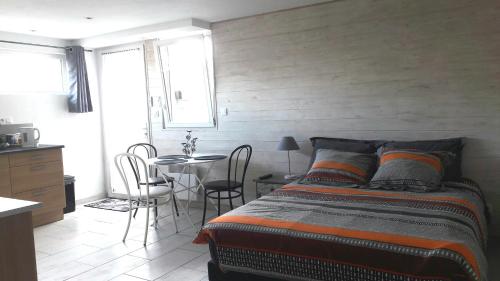 阿貢庫坦維爾的住宿－STUDIO PROCHE DE LA MER，卧室配有一张床和一张桌子及椅子