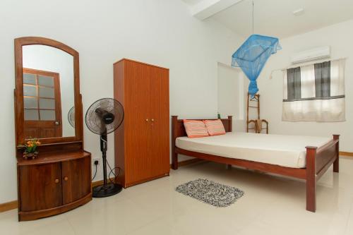 um quarto com uma cama, um espelho e uma ventoinha em Sena Home em Ambalangoda