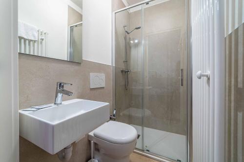 uma casa de banho com um WC, um lavatório e um chuveiro em Appartamento Dolomia em Caprile