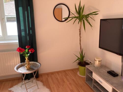 ein Wohnzimmer mit einem TV und einem Tisch mit Blumen in der Unterkunft Sternenhimmel Gamlitz FeWo 3 SZ in Gamlitz