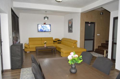 a living room with a yellow couch and a table at Camere Centrale in Piteşti