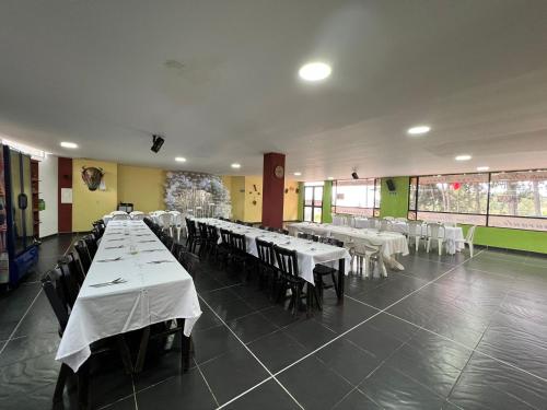 a dining room with tables and chairs with white tablecloths at Hotel Playa Blanca in Tota
