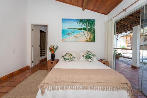 um quarto com uma cama e um quadro na parede em Casa Caminho do Mar (TRANCOSO-BA) em Trancoso