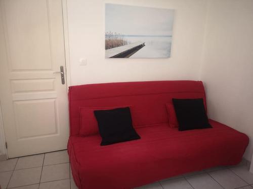 a red couch with two black pillows on it at Studio Chaleureux in Albert