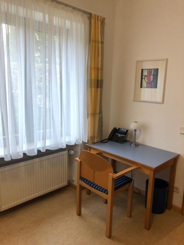 a desk and a chair in a room with a window at Spectrum Kirche Exerzitien-und Bildungshaus auf Mariahilf in Passau