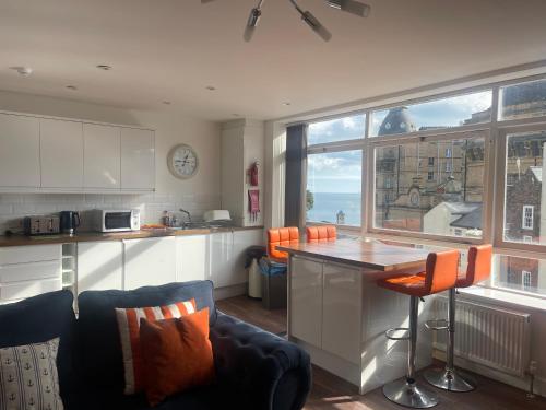 a kitchen with an island with orange chairs and a counter at Harcourt Place in Scarborough
