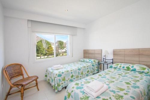 a bedroom with two beds and a chair and a window at Isabela 2a 3 habitaciones con ático in Port de Pollensa