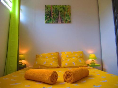 Un dormitorio con una cama amarilla con toallas. en L'hibiscus By Nid'Ouest - Grand T3 - Parking privé, en Le Lamentin