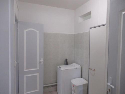a white bathroom with a toilet and a door at L'hibiscus By Nid'Ouest - Grand T3 - Parking privé in Le Lamentin