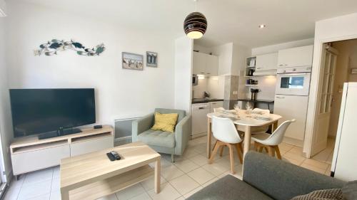 un salon avec une télévision et une table avec des chaises dans l'établissement Superbe apt cosy, 50m de la plage, 4 pers, vue côté mer, à Fort-Mahon-Plage