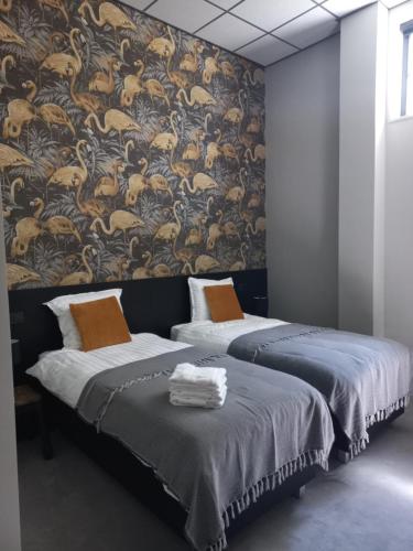 two beds in a room with a wall mural at Boutique Hotel De Oude Veste in Hellevoetsluis