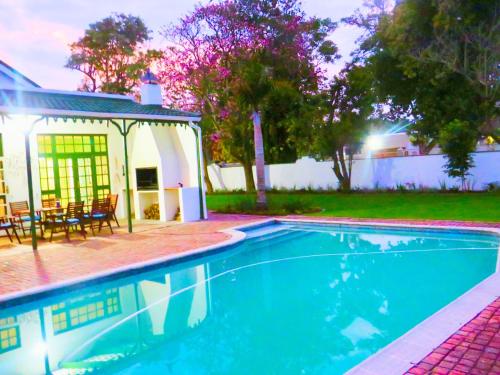 a swimming pool in front of a house at Whistlewood Guesthouse Walmer, Port Eizabeth in Port Elizabeth
