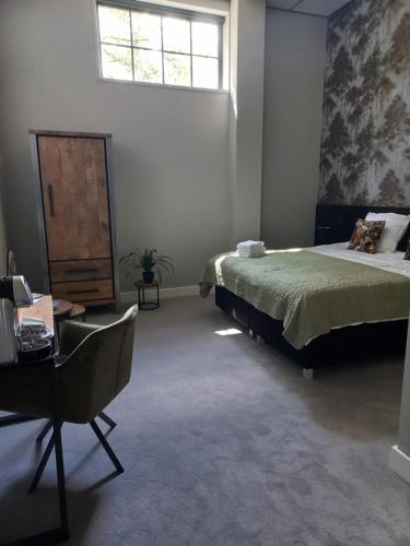 a bedroom with a bed and a desk and a window at Boutique Hotel De Oude Veste in Hellevoetsluis