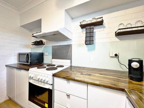 a kitchen with a stove and a microwave at Manhattan - Stylish 1BR Beachfront on Caseys in Batehaven