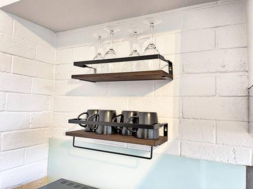 a kitchen with a shelf with pots on it at Manhattan - Stylish 1BR Beachfront on Caseys in Batehaven