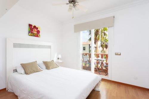 a white bedroom with a bed and a balcony at LUXURY VILLA WITH PRIVATE POOL WITH AIRCON,Playa del Duque in Adeje
