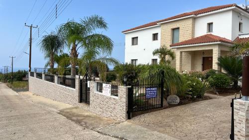a house with a fence and palm trees on a street at Nayia Paradise Villa! Best Villa in Cyprus in Paphos City