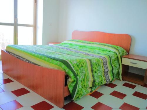 een slaapkamer met een bed met een groene deken erop bij La dolce vita, relax & kite Falerna in Falerna