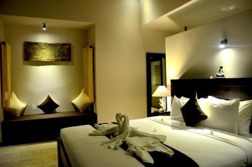 ein Hotelzimmer mit einem großen Bett mit weißer Bettwäsche in der Unterkunft Pandawa Village in Lovina