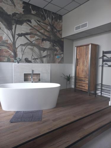 a bath tub in a bathroom with a painting on the wall at Boutique Hotel De Oude Veste in Hellevoetsluis