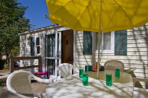 einen Tisch mit einem gelben Regenschirm vor einem Haus in der Unterkunft Camping Paradis Le Pressoir in Petit-Palais-et-Cornemps