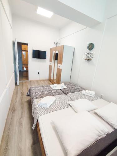 two beds in a white room with a tv at Sole Mio Apartment & Wellness in Herceg-Novi