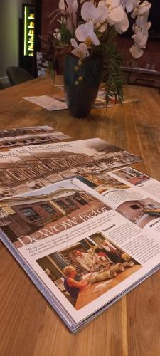 a table topped with magazines and a vase of flowers at Boutique Hotel De Oude Veste in Hellevoetsluis
