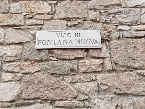 a white sign on a stone wall at Fontana Nuova in Sardara