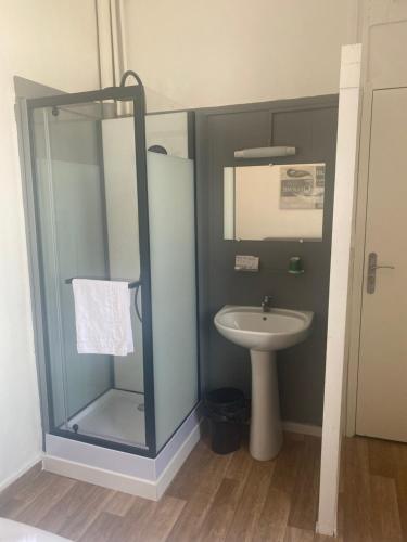 ein Bad mit einer Glasdusche und einem Waschbecken in der Unterkunft HOTEL DU CENTRE in Roubaix