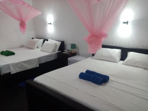 2 Betten mit rosa und blauen Kissen darauf in der Unterkunft Peacock Garden in Tangalle