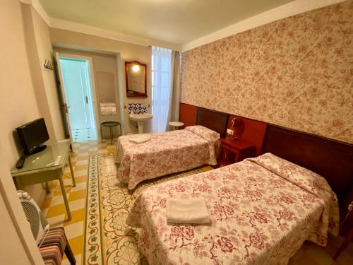 a hotel room with two beds and a desk at Pensión España in Cádiz