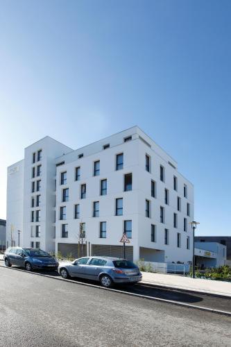 two cars parked in front of a white building at Appart'City Classic Rennes Beauregard in Rennes