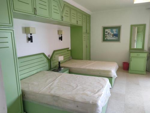 Marena Hurghada في الغردقة: سريرين في غرفة مع دواليب خضراء