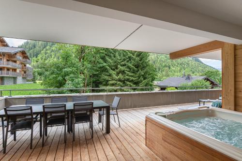 une terrasse avec une table et des chaises ainsi qu'un bain à remous dans l'établissement Quintessence- Apt B101- BO Immobilier - Châtel - Multipass 2025 offert, à Châtel