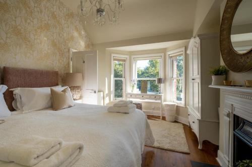 a bedroom with a bed with white sheets and a fireplace at The Bend in Bransgore