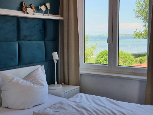 a bedroom with a bed and a large window at Haus Achtern Diek in erster Reihe am Meer in Fehmarn
