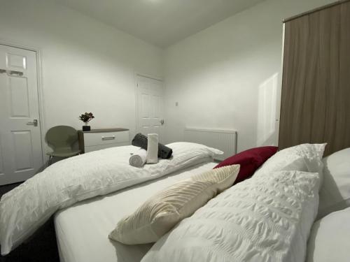 um quarto com 2 camas com lençóis brancos e almofadas em Nice Living Serviced Accommodations 3 em Coventry