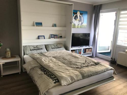 ein Schlafzimmer mit einem großen Bett und einem TV in der Unterkunft Haus Westerhörn am Strand in Westerland