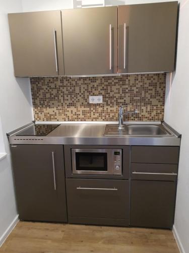 a kitchen with a sink and a microwave at Haus Achtern Diek in erster Reihe am Meer in Fehmarn
