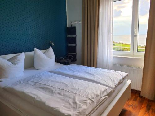 a bedroom with a white bed with a window at Haus Achtern Diek in erster Reihe am Meer in Fehmarn