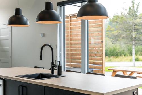 a kitchen with black pendant lights and a sink at Initial / Lagom / MSA in Saint-Férréol-les-Neiges