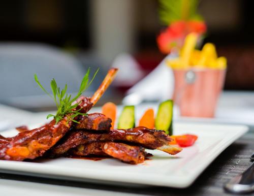 a plate of food with meat and vegetables on a table at Crowne Plaza - Dar Es Salaam by IHG in Dar es Salaam