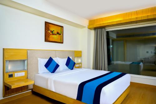 um quarto com uma grande cama branca com almofadas azuis em Keyonn Hotels & Resorts em Amritsar